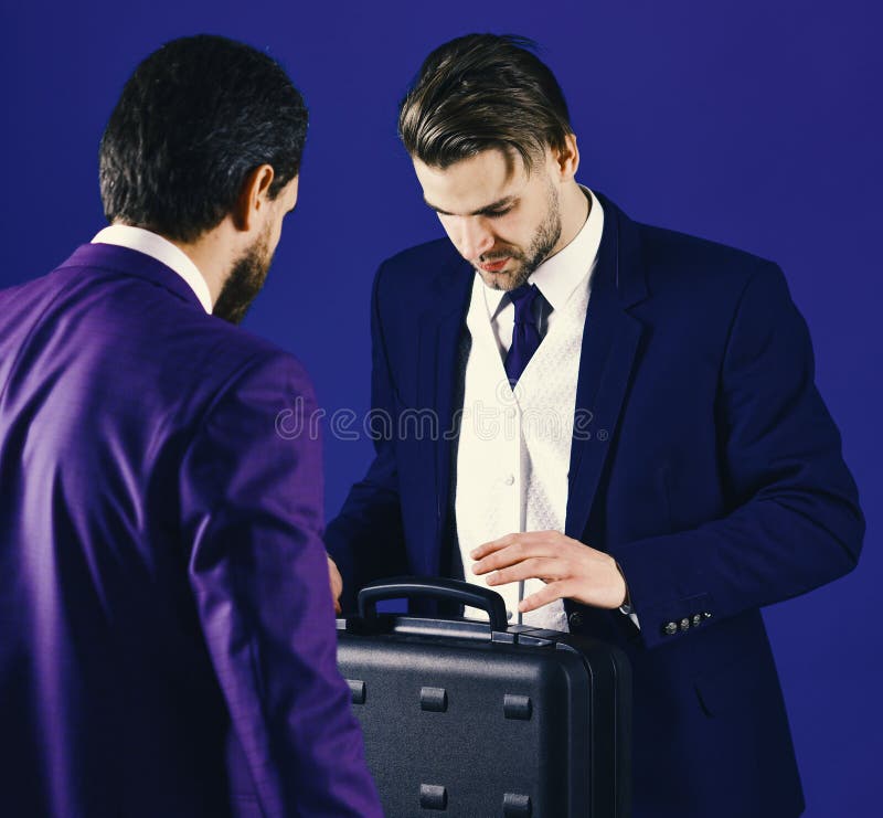De mensen in kostuum of de zakenlieden komen voor overdracht van zwarte aktentas samen Partners met bezig gezicht op blauwe achte royalty-vrije stock foto De mensen in kostuum of de zakenlieden komen voor overdracht van zwarte aktentas samen Partners met bezig gezicht op blauwe achte royalty-vrije stock foto