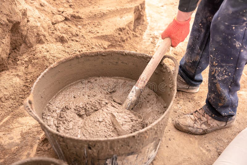 De metselaar kneedt cementmortier voor het gieten van concrete screed royalty-vrije stock fotografie De metselaar kneedt cementmortier voor het gieten van concrete screed royalty-vrije stock fotografie