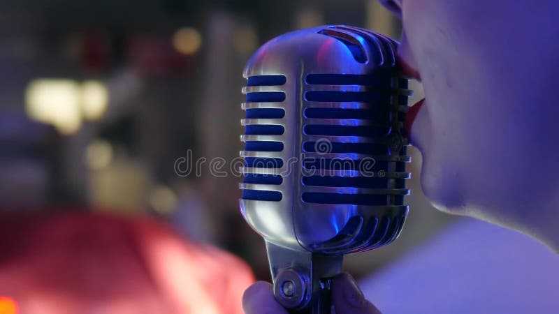 De microfoon in handen van meisje met rode lippen unfocused achtergrond