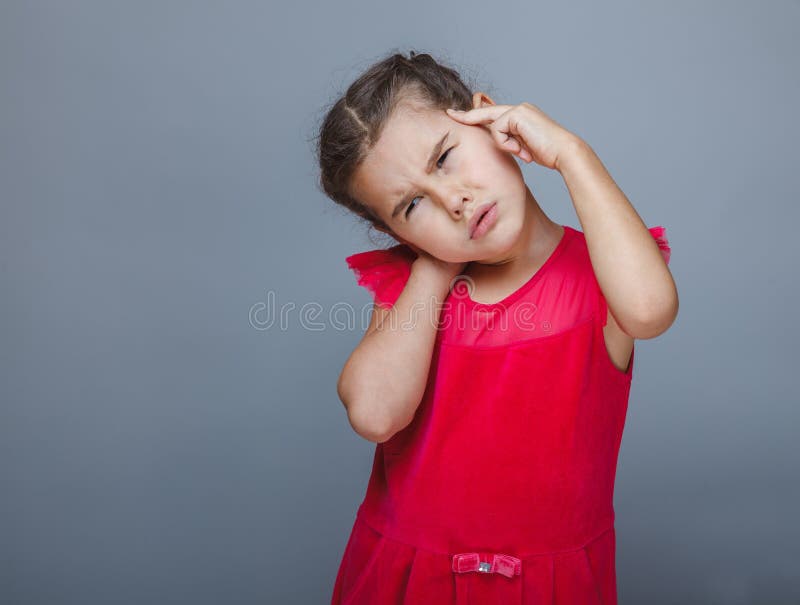 De migraine die van de het kindhoofdpijn van het tienermeisje zijn hoofd op grijze bac houden royalty-vrije stock foto De migraine die van de het kindhoofdpijn van het tienermeisje zijn hoofd op grijze bac houden royalty-vrije stock foto