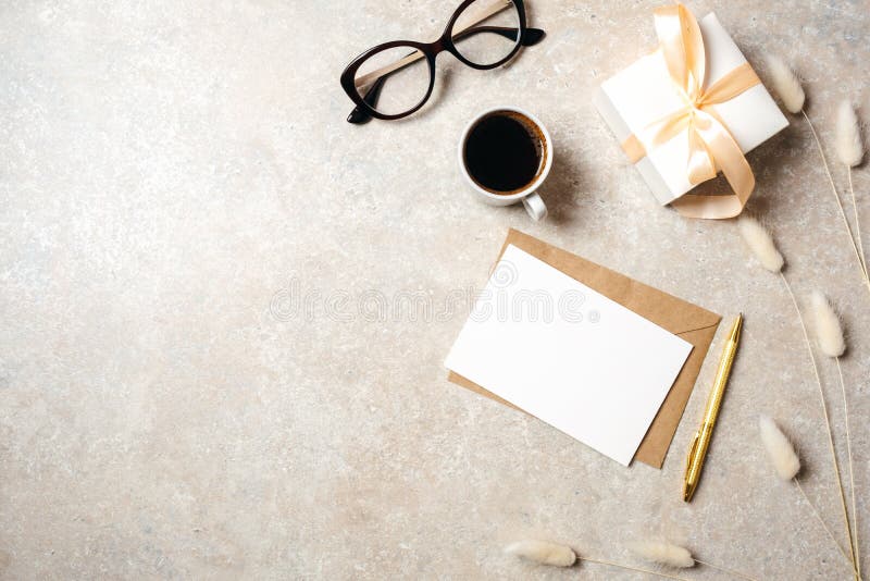 De minimale werkruimte van het huisbureau met lege document kaart, kraftpapier-envelop, koffiekop, giftvakje, droge bloemen, glaz royalty-vrije stock afbeeldingen De minimale werkruimte van het huisbureau met lege document kaart, kraftpapier-envelop, koffiekop, giftvakje, droge bloemen, glaz royalty-vrije stock afbeeldingen