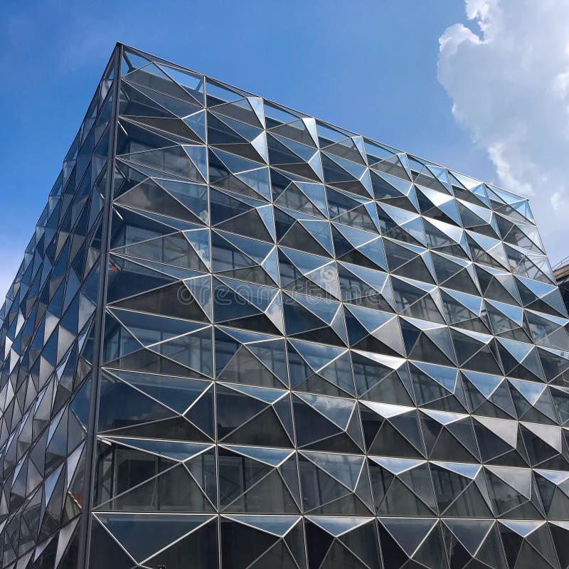 De moderne futuristische bureaubouw met bezinning van wolken en blauwe hemel op de glasvensters royalty-vrije stock afbeeldingen De moderne futuristische bureaubouw met bezinning van wolken en blauwe hemel op de glasvensters royalty-vrije stock afbeeldingen