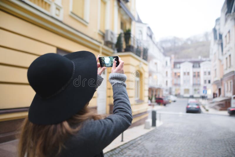 De modieuze vrouwentoerist maakt een foto van architectuur Het meisje is bezig geweest met mobiele fotografie royalty-vrije stock afbeeldingen De modieuze vrouwentoerist maakt een foto van architectuur Het meisje is bezig geweest met mobiele fotografie royalty-vrije stock afbeeldingen