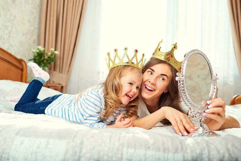 De moeder en de dochter met kronen op het hoofd spelen op B stock fotografie De moeder en de dochter met kronen op het hoofd spelen op B stock fotografie