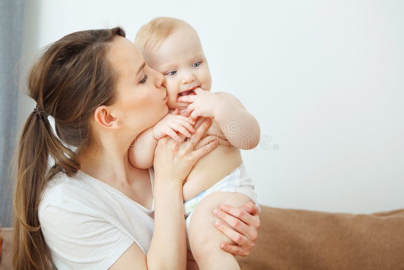 De moeder kust haar kind, houdt de baby zijn vinger dichtbij mond stock afbeelding De moeder kust haar kind, houdt de baby zijn vinger dichtbij mond stock afbeelding