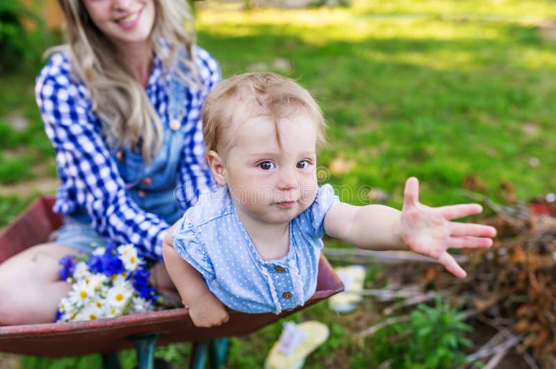 De moeder met de kleine dochter zit in de tuinkar in het dorp stock fotografie De moeder met de kleine dochter zit in de tuinkar in het dorp stock fotografie