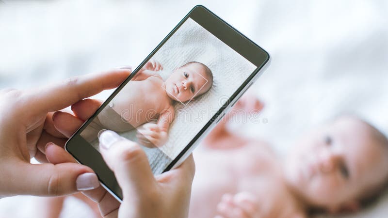 De moeder neemt een smartphonefoto van haar pasgeboren baby stock foto's De moeder neemt een smartphonefoto van haar pasgeboren baby stock foto's