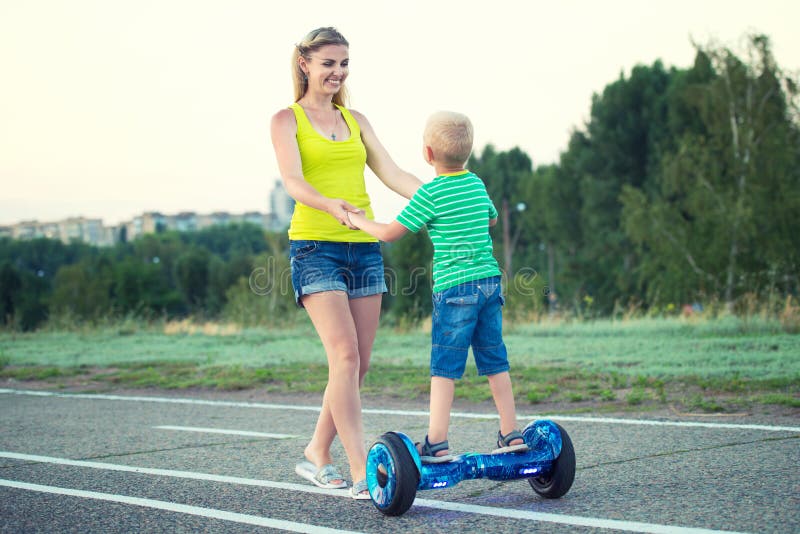 De moeder onderwijst haar weinig zoon om op saldoraad te berijden stock foto's De moeder onderwijst haar weinig zoon om op saldoraad te berijden stock foto's