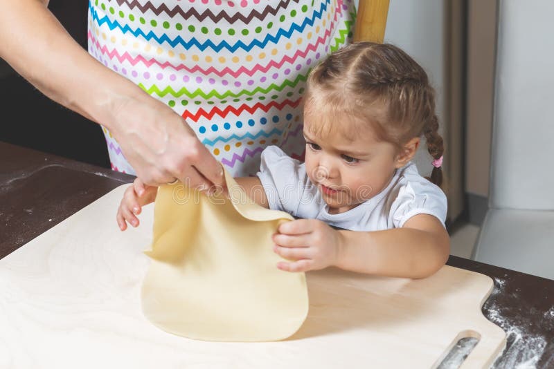 De moeder toont weinig dochter hoe te om het deeg te koken voor het maken van koekjes stock fotografie De moeder toont weinig dochter hoe te om het deeg te koken voor het maken van koekjes stock fotografie