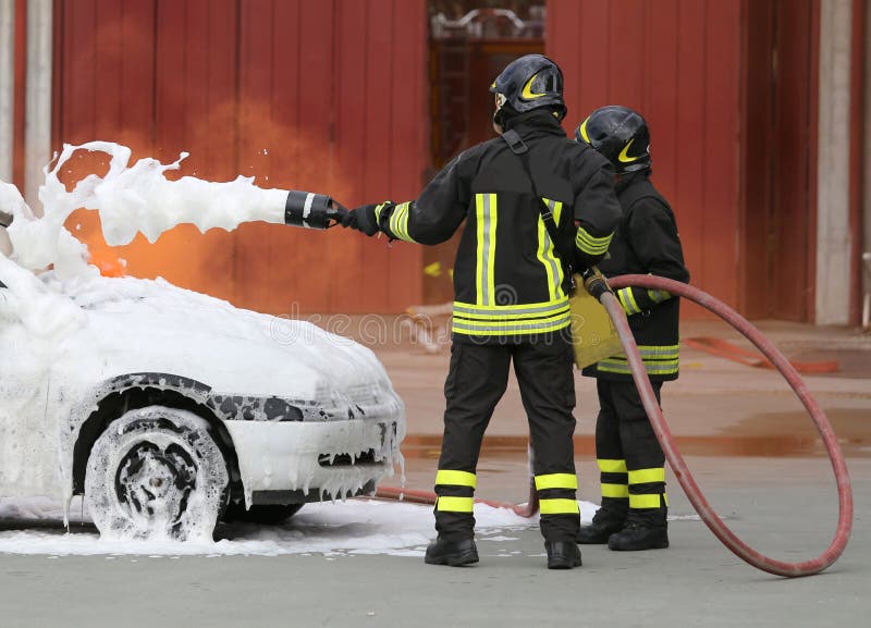 de moedige brandbestrijders met schuimende brand van de auto steken na in brand stock foto de moedige brandbestrijders met schuimende brand van de auto steken na in brand stock foto