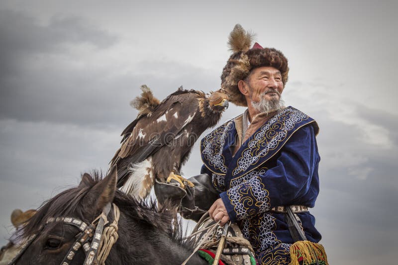 Bayan Ulgii, Mongolia, October 2nd, 2015: Old eagle hunter with his Altai Golden Eagle on his horse. Bayan Ulgii, Mongolia, October 2nd, 2015: Old eagle hunter with his Altai Golden Eagle on his horse