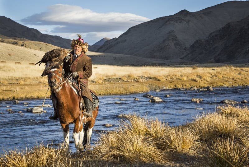 Bayan Ulgii, Mongolia, October 2nd, 2015: Old eagle hunter with his Altai Golden Eagle on his horse. Bayan Ulgii, Mongolia, October 2nd, 2015: Old eagle hunter with his Altai Golden Eagle on his horse