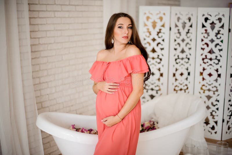 De mooie donkerbruine zwangere vrouw kleedde zich in kleding royalty-vrije stock afbeeldingen De mooie donkerbruine zwangere vrouw kleedde zich in kleding royalty-vrije stock afbeeldingen