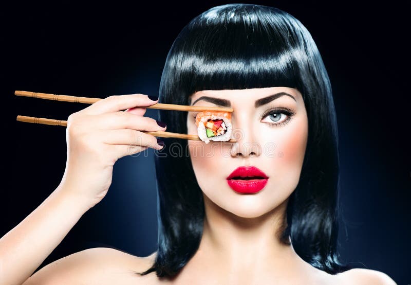 De mooie eetstokjes van de vrouwenholding met sushibroodje stock foto De mooie eetstokjes van de vrouwenholding met sushibroodje stock foto