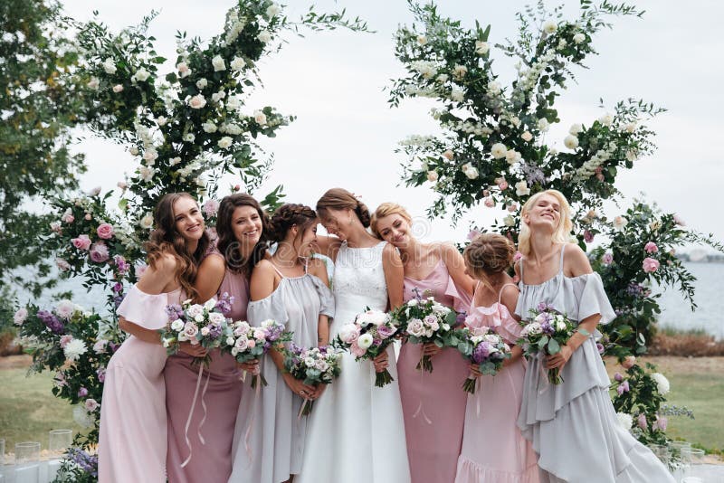 De mooie elegante slanke glimlachende bruidsmeisjes in de gevoelige roze beige zomer kleden zich op de huwelijksceremonie