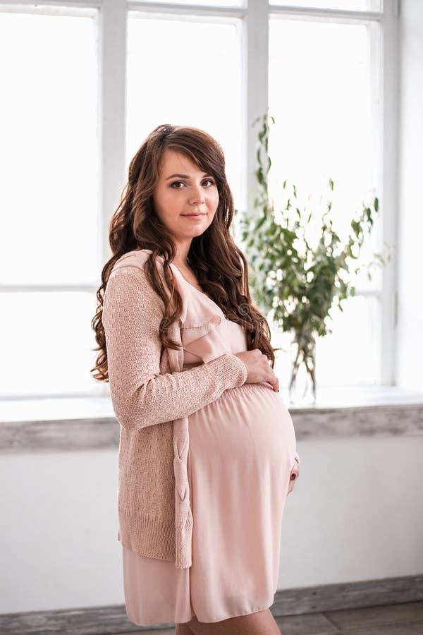 De mooie glimlachende zwangere vrouw houdt buik stock foto's De mooie glimlachende zwangere vrouw houdt buik stock foto's