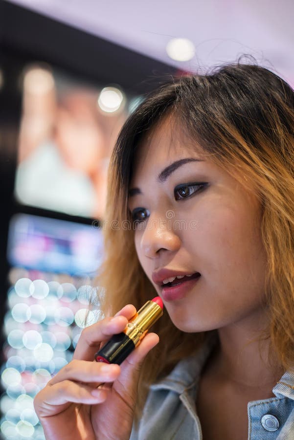 De mooie jonge lippenstift van de vrouwen uitgezochte kleur aan het kopen bij het winkelen stock afbeelding De mooie jonge lippenstift van de vrouwen uitgezochte kleur aan het kopen bij het winkelen stock afbeelding