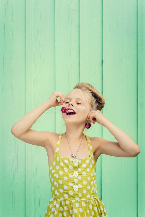 De mooie kersen van de meisjesholding als oorringen - stijl Rockabilly stock fotografie De mooie kersen van de meisjesholding als oorringen - stijl Rockabilly stock fotografie