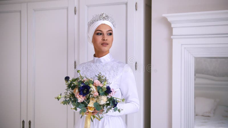 De mooie moslimbruid met maakt omhoog in huwelijkskleding met wit hoofddeksel