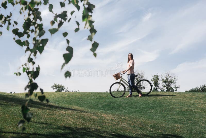 De mooie vrouw loopt in het park met fiets royalty-vrije stock afbeeldingen