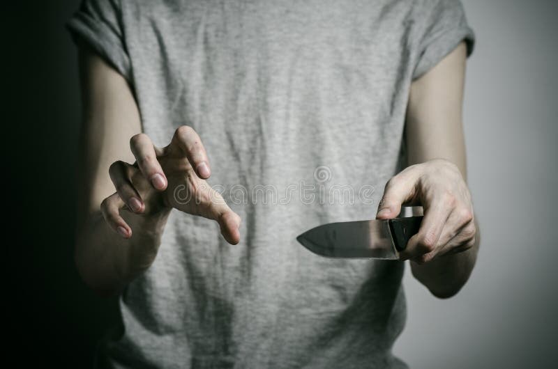De moord en Halloween als thema hebben: een mens die een mes op een grijze achtergrond houden stock afbeelding De moord en Halloween als thema hebben: een mens die een mes op een grijze achtergrond houden stock afbeelding
