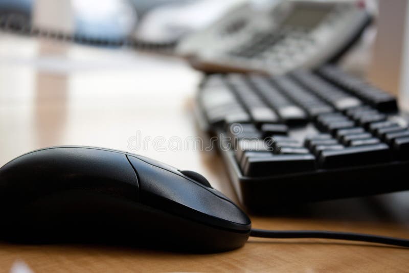 Close up of a modern office workplace desk setup with a computer mouse keyboard and phone. Shallow depth of field. Close up of a modern office workplace desk setup with a computer mouse keyboard and phone. Shallow depth of field.