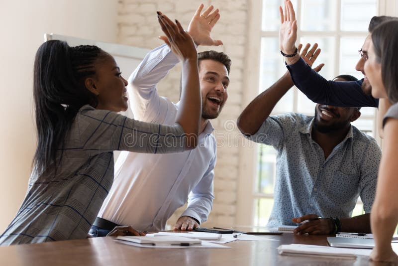 De multiraciale euforische commerciële teammensen geven hoogte vijf in bureau