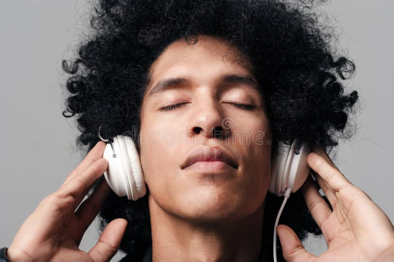 Portrait of a dj man listening to music on headphones with afro hairstyle isolated on grey background. Portrait of a dj man listening to music on headphones with afro hairstyle isolated on grey background