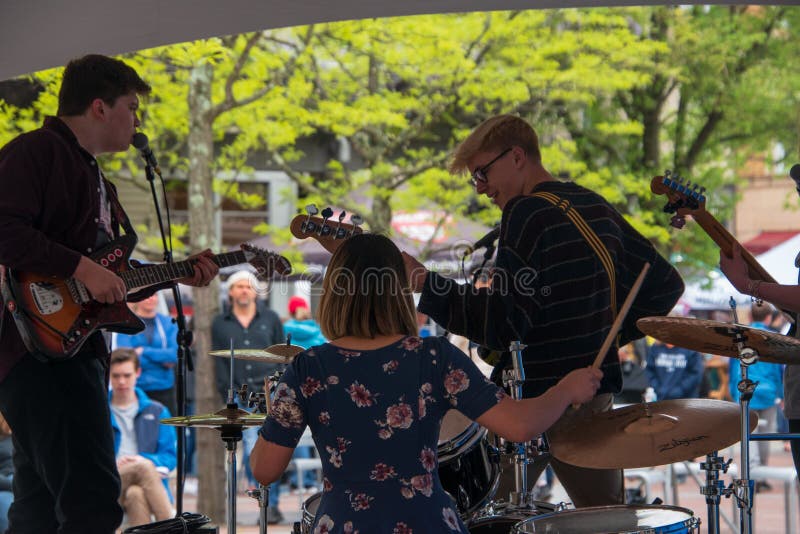 De muzikale groep wordt gezien van de rug aangezien zij hun instrumenten voor een menigte bij een openluchtmarkt spelen Er is een stock afbeelding De muzikale groep wordt gezien van de rug aangezien zij hun instrumenten voor een menigte bij een openluchtmarkt spelen Er is een stock afbeelding