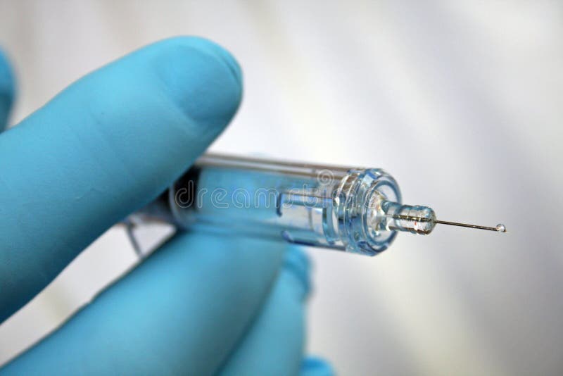 De naald van de injectie die door gloved hand wordt gehouden stock afbeeldingen De naald van de injectie die door gloved hand wordt gehouden stock afbeeldingen