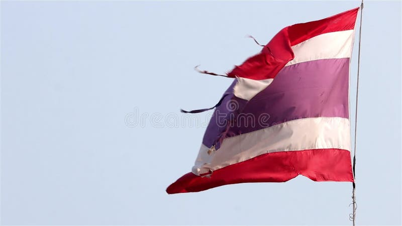 De nationale vlag van thailand verscheurt op een touw tegen een blauwe hemel met een langzame beweging