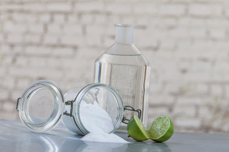 Natural cleaning products, including sodium bicarbonate, invert jar, baking soda, lemon, vinegar,on grey table on old grey wall. Natural cleaning products, including sodium bicarbonate, invert jar, baking soda, lemon, vinegar,on grey table on old grey wall