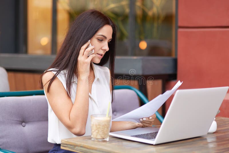 De onderneemster heeft telefoongesprek, bestudeert bedrijfsdocumentatie, financiële analyse, zit voor geopende laptop royalty-vrije stock afbeeldingen De onderneemster heeft telefoongesprek, bestudeert bedrijfsdocumentatie, financiële analyse, zit voor geopende laptop royalty-vrije stock afbeeldingen