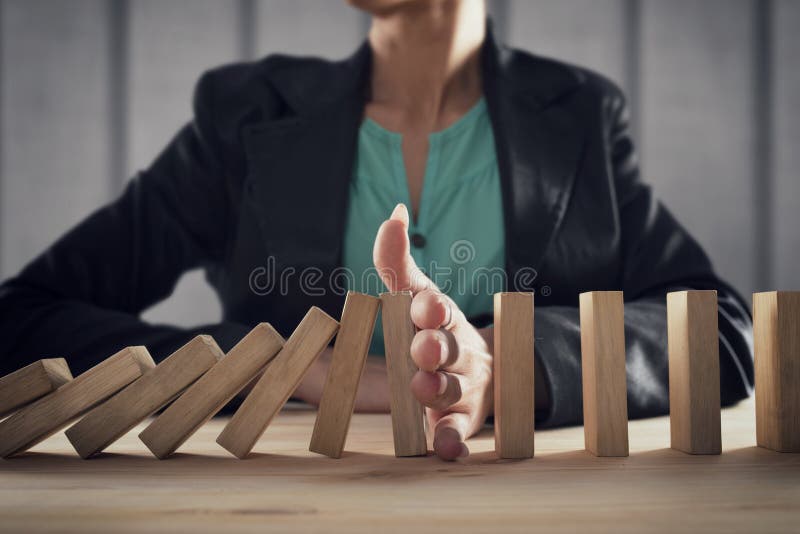 Businesswoman stops a chain fall like domino game toy. Concept of preventing crisis and failure in business. Businesswoman stops a chain fall like domino game toy. Concept of preventing crisis and failure in business