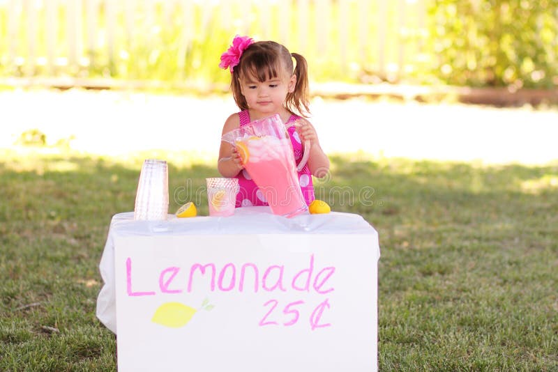 Cute toddler girl entrepreneur open for business selling pink lemonade on a hot summer day. Cute toddler girl entrepreneur open for business selling pink lemonade on a hot summer day.