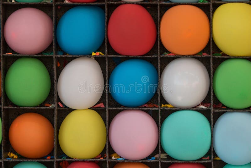 Inflated balloons waiting to be popped sit on shelves of carnival game at county fair, along with the remnants of several popped balloons. Inflated balloons waiting to be popped sit on shelves of carnival game at county fair, along with the remnants of several popped balloons.