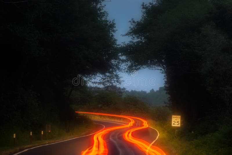 De oranje, rode en gele auto lichte slepen langs een wegkromme in de bergen bij nacht met maximum snelheid ondertekenen Vervoer, stock afbeelding De oranje, rode en gele auto lichte slepen langs een wegkromme in de bergen bij nacht met maximum snelheid ondertekenen Vervoer, stock afbeelding
