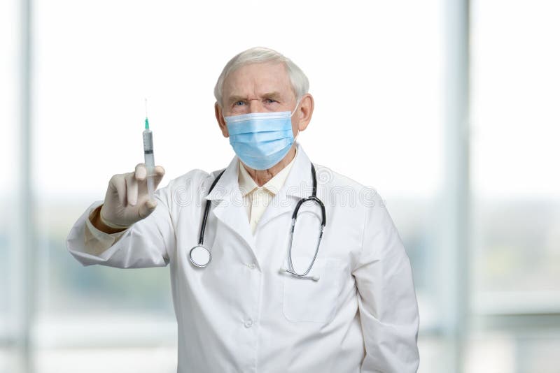 De oude ernstige spuit van de artsenholding met vaccin royalty-vrije stock fotografie De oude ernstige spuit van de artsenholding met vaccin royalty-vrije stock fotografie