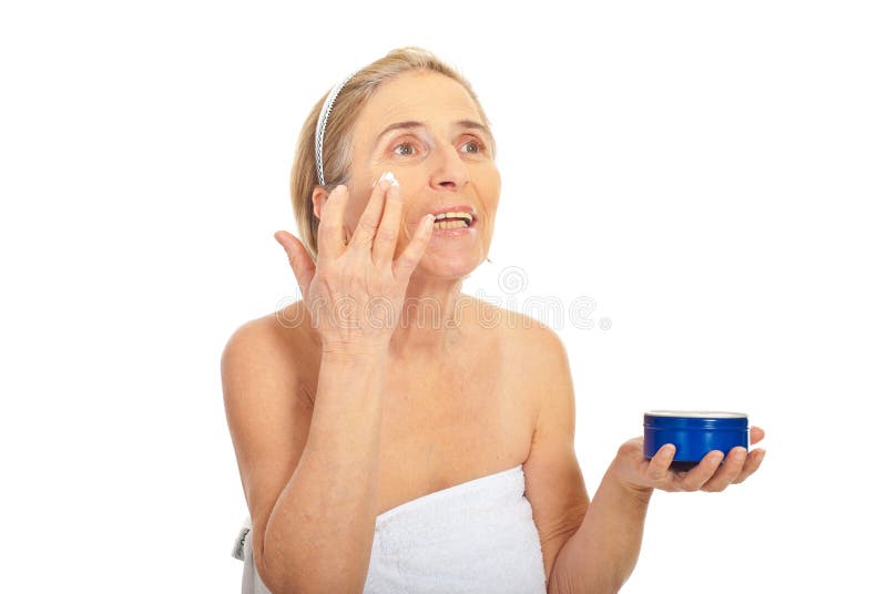 Older woman applying skin care cream and looking away isolated on white background. Older woman applying skin care cream and looking away isolated on white background