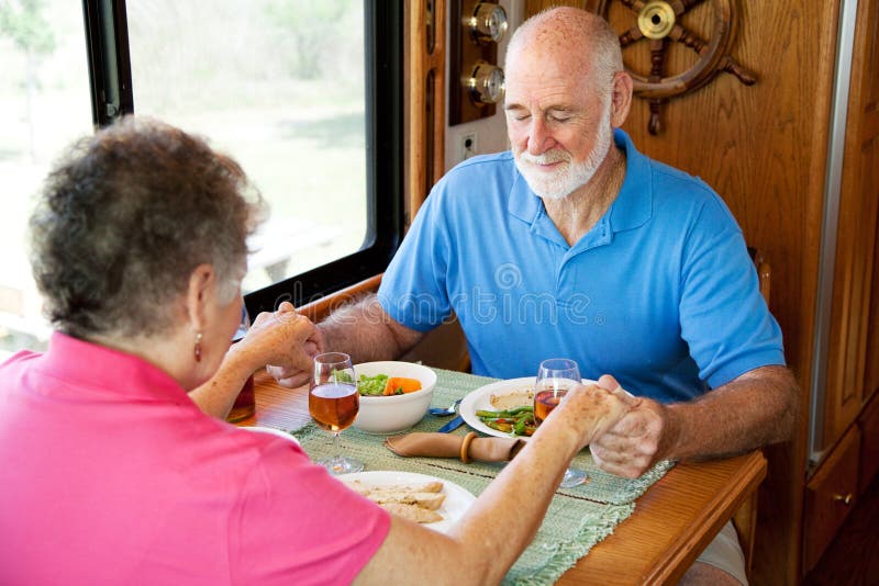 Christian senior couple in their motor home, saying grace over their meal. Christian senior couple in their motor home, saying grace over their meal.