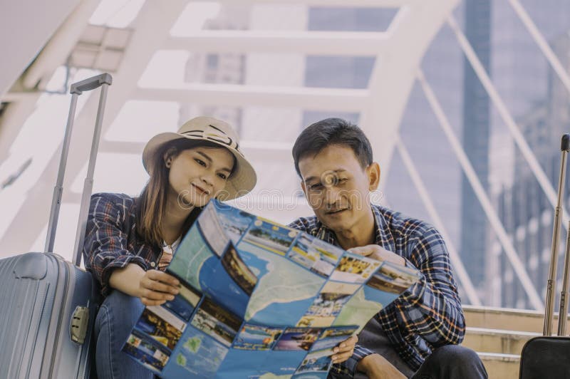 De parenreizigers, lezen de kaart aan planreis op platform i stock fotografie De parenreizigers, lezen de kaart aan planreis op platform i stock fotografie