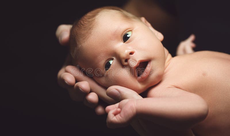 Pasgeboren baby in de handen van zijn vader in het donker royalty-vrije stock foto's