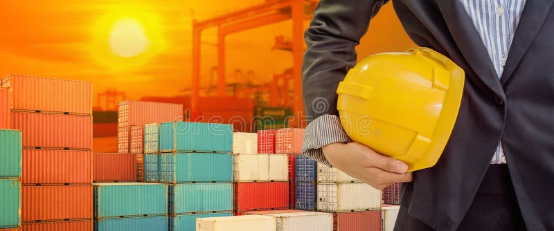 De persoon die gele helm voor arbeidersveiligheid houden op industrieel havenachtergrond en licht glanst zonsondergang stock afbeeldingen De persoon die gele helm voor arbeidersveiligheid houden op industrieel havenachtergrond en licht glanst zonsondergang stock afbeeldingen