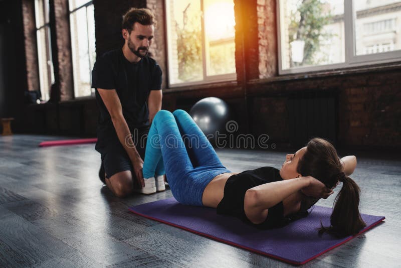 De persoonlijke trainer helpt een meisje met de gymnastiekoefeningen stock afbeeldingen De persoonlijke trainer helpt een meisje met de gymnastiekoefeningen stock afbeeldingen