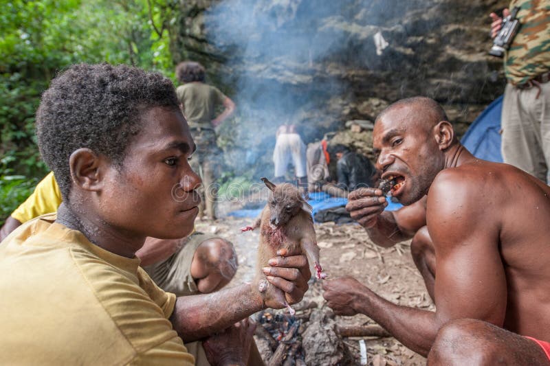 De plaatselijke bewoners van het eiland Nieuw-Guinea hebben diner de gevangen vliegvos royalty-vrije stock afbeelding De plaatselijke bewoners van het eiland Nieuw-Guinea hebben diner de gevangen vliegvos royalty-vrije stock afbeelding