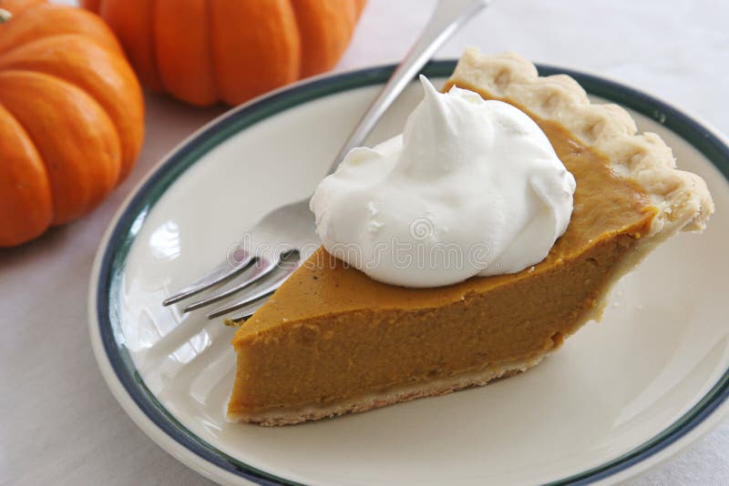 A slice of pumpkin pie with whipped cream and a fork. A slice of pumpkin pie with whipped cream and a fork.