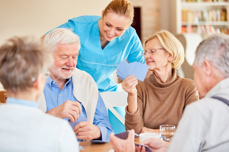 Nursing lady looks curious while playing cards of seniors in retirement home. Nursing lady looks curious while playing cards of seniors in retirement home