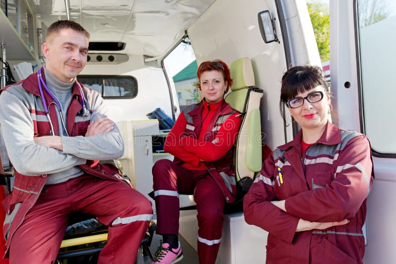 De positieve Arts van ER met Paramedicicollega's in Ziekenwagenauto stock foto De positieve Arts van ER met Paramedicicollega's in Ziekenwagenauto stock foto