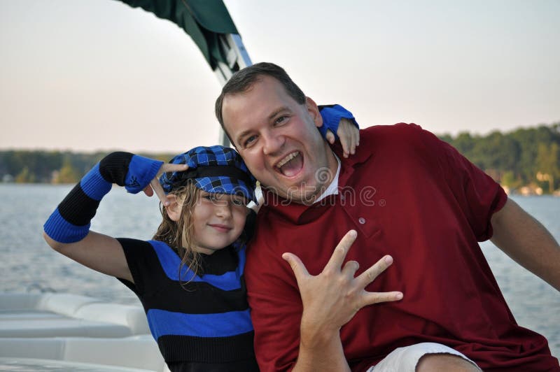 A father and daughter make a playful hip-hop pose while boating in summer. A father and daughter make a playful hip-hop pose while boating in summer