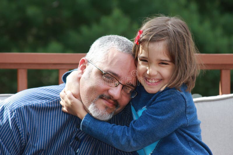 An adorable girl is hugging to her dad with a happy expression in her face. An adorable girl is hugging to her dad with a happy expression in her face.